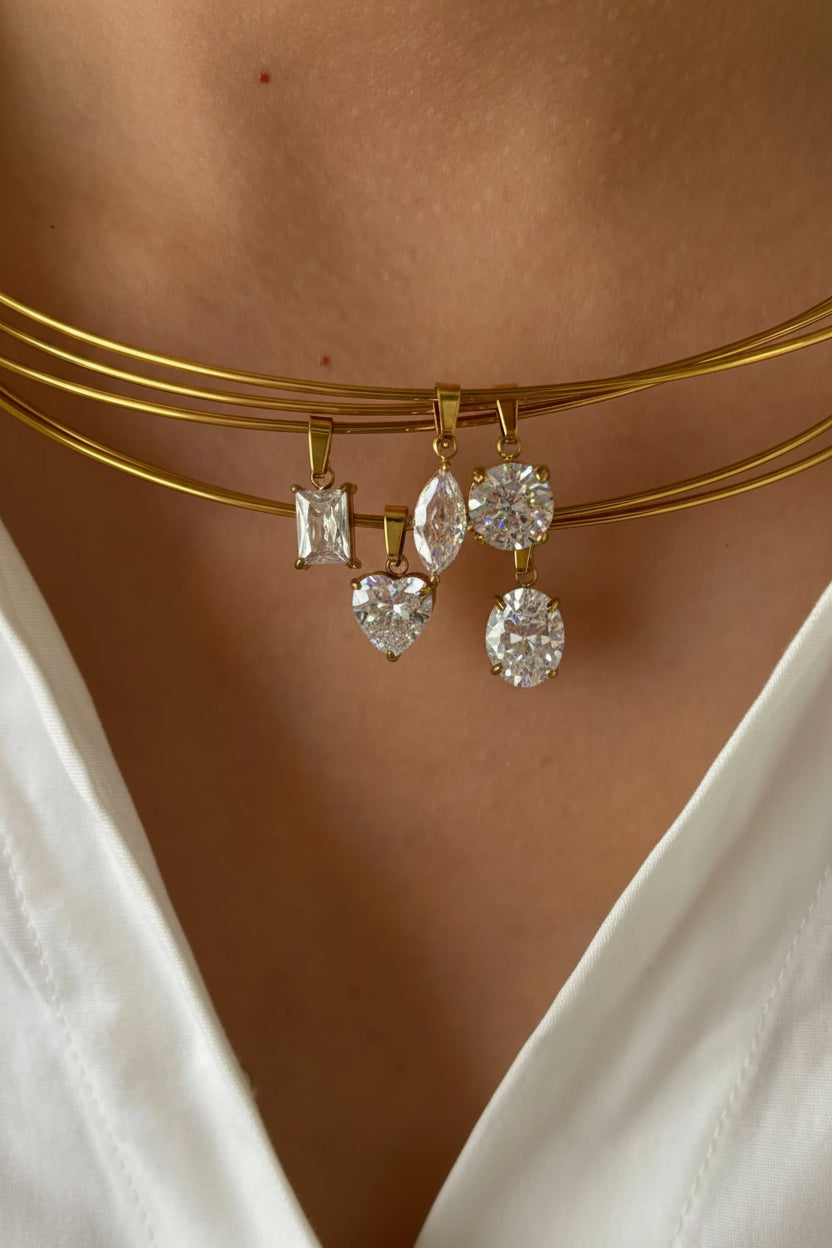 Gold necklace with dangling diamond pendants on a person wearing a white top.